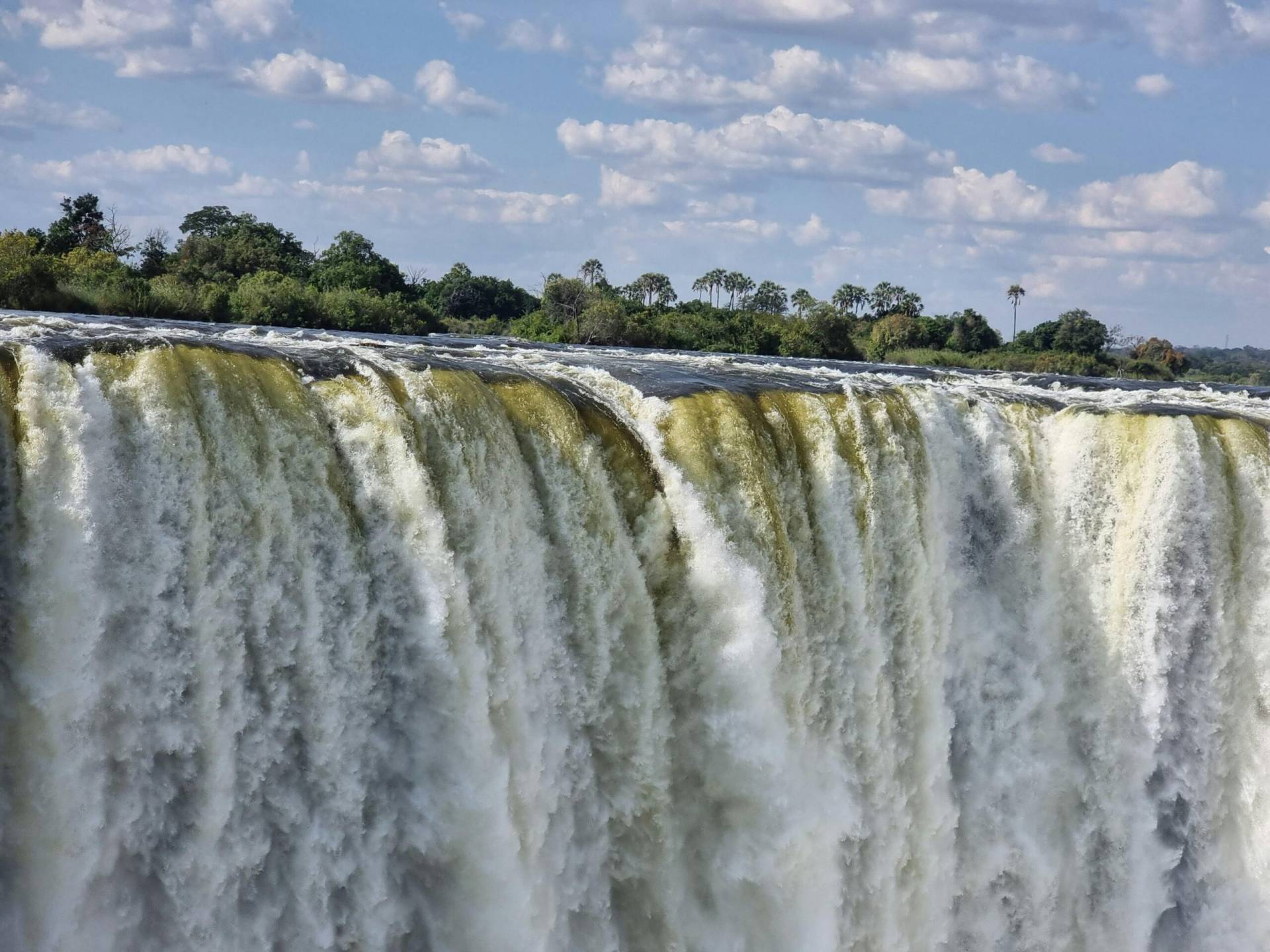 Stunning view of Victoria Falls cascading with vibrant energy, surrounded by lush greenery.