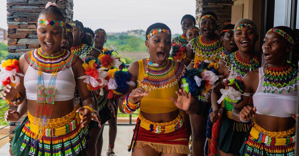 A group of Zulu women in traditional attire dancing passionately outdoors, showcasing vibrant cultural heritage.
